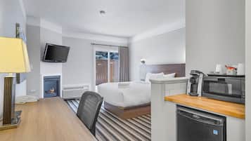 Quarto de hotel com cama, escrivaninha, televisão, máquina de café e micro-ondas.