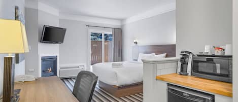 Una habitación de hotel con cama, escritorio, televisor, cafetera y microondas.