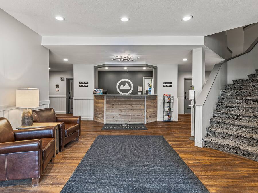 A reception area with a reception desk, leather seating, a staircase, and a wooden floor.
