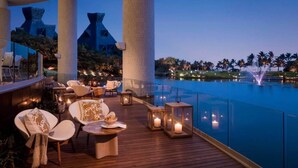 A rooftop bar with wooden flooring, lounge chairs, and candles.