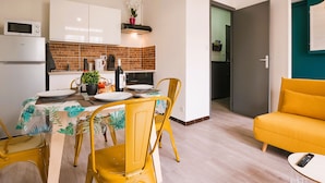 A compact living space with a dining area, kitchenette, and a sofa.