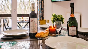 A dining table with plates, cutlery, a bottle of wine, a candle, and a small plant.