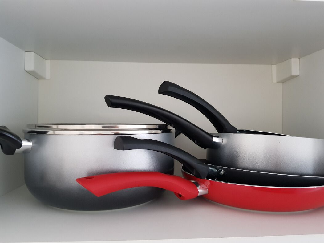 A kitchen with stainless steel pots and pans on a white countertop.