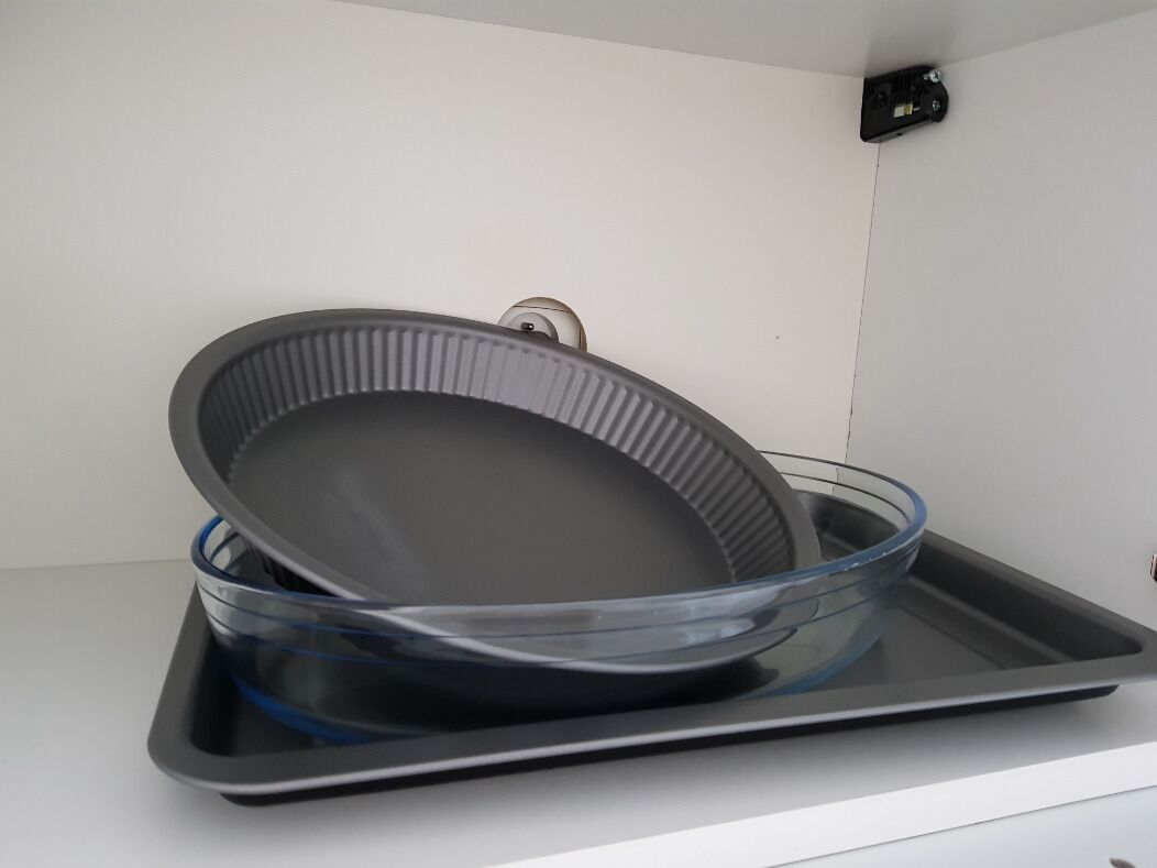 A kitchen with a black tray and a glass bowl on a white countertop.