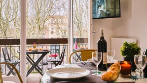 A dining area with a table set for two, a bottle of wine, a candle, and a loaf of bread.
