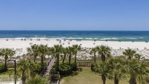 A beach with palm trees, umbrellas, and a clear blue sky. - Regency Isle 307 | Beachfront | Pools, Hot Tubs and more! | My Beach Getaways (Orange Beach)