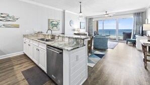 A modern kitchen with a marble countertop, white cabinetry, and a built-in dishwasher. - Regency Isle 307 | Beachfront | Pools, Hot Tubs and more! | My Beach Getaways (Orange Beach)