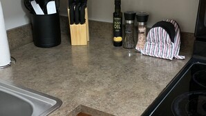 Une cuisine dotée d’un plan de travail en granit, de meubles en bois, d’un évier en acier inoxydable et d’une cuisinière noire.