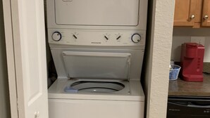 Un lave-linge et un sèche-linge compacts, installés dans une cuisine dotée de meubles en bois et d’un lave-vaisselle.