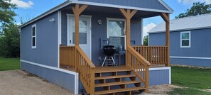 Ein kleines, einstöckiges Gebäude mit Veranda und Grill.