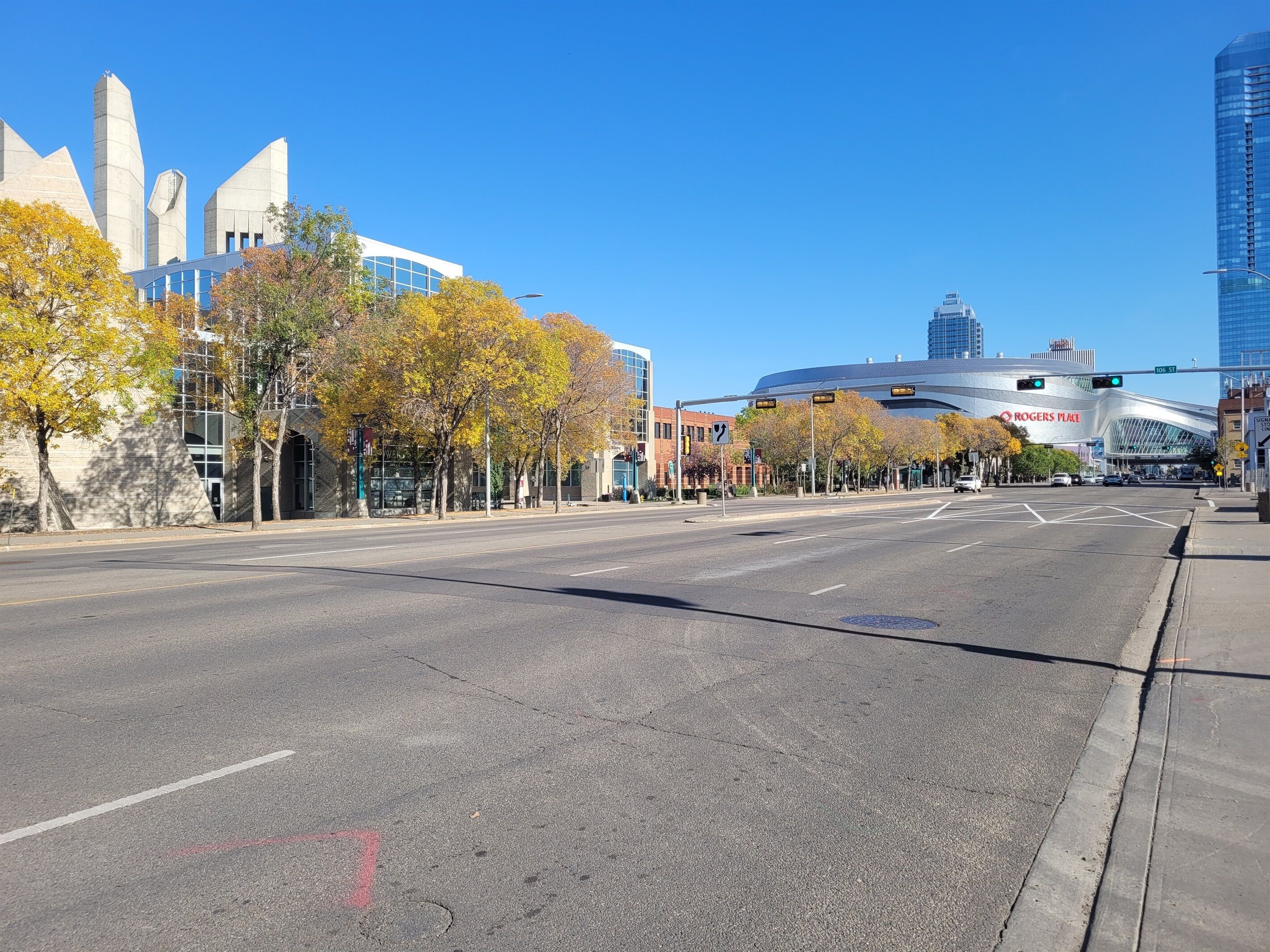 Una amplia avenida urbana con edificios modernos, incluyendo una estructura curva distintiva identificada como 'Rogers Place'.