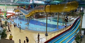 Parque acuático interior con múltiples toboganes y piscinas.