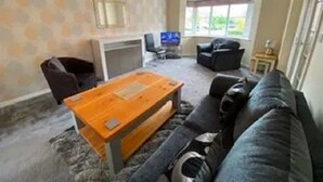 A living room with a sofa, a coffee table, a television, and a fireplace. - 5 BEDROOM / 4 BATHROOM MODERN DETACHED  wifi  Garden  Parking  Quiet location (Newcastle-under-Lyme)