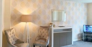 Une pièce comprenant deux fauteuils, une lampe, un téléviseur et une petite table.