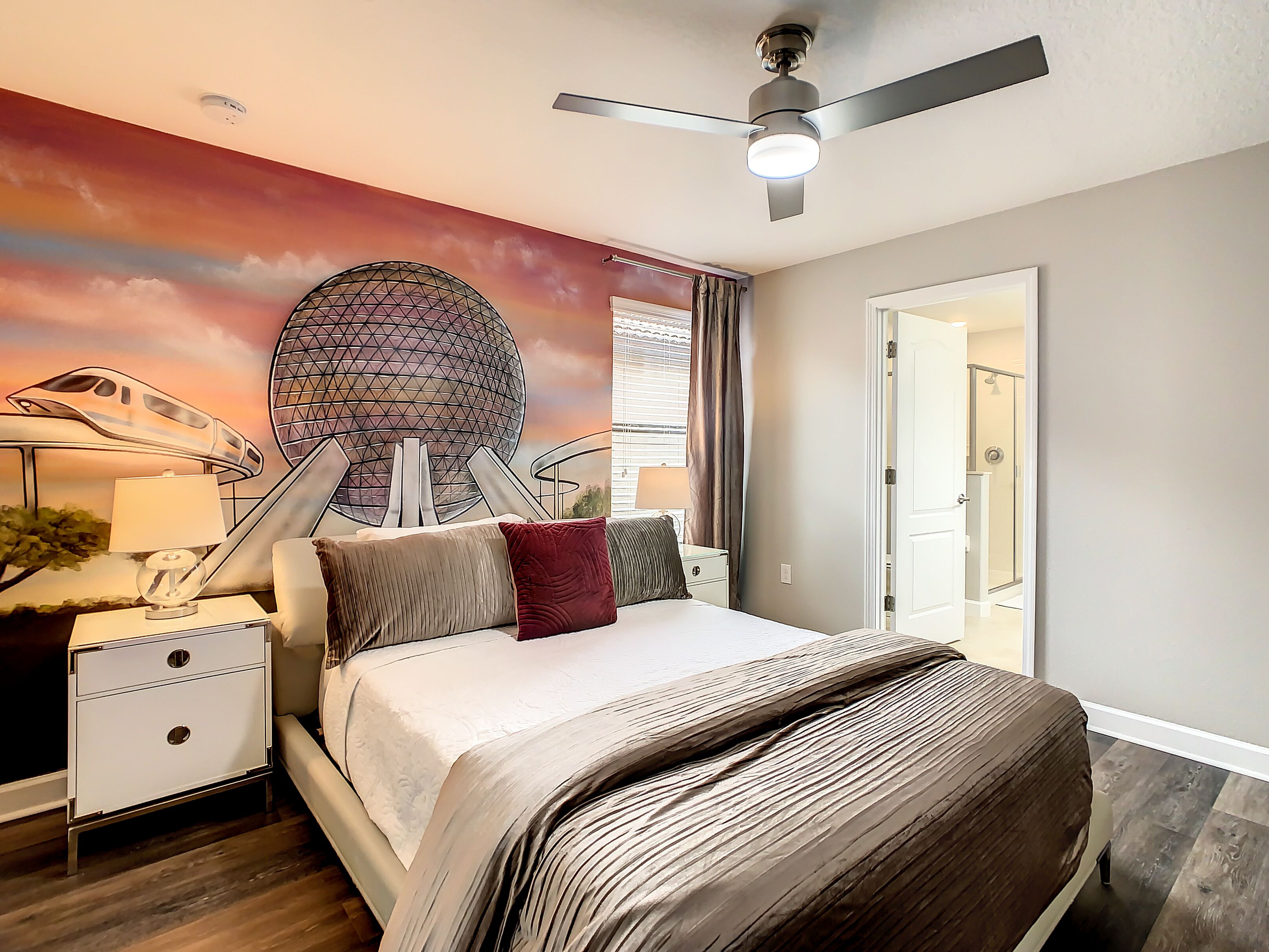 A modern bedroom with a bed, nightstands, a lamp, a ceiling fan, and a mural of futuristic structures.