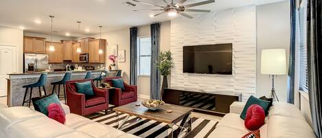 A modern living room with a sofa, chairs, a coffee table, and a TV mounted on the wall.