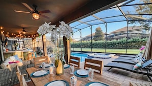 Un espace repas avec vue sur la piscine, doté de meubles en bois et d’un espace clos par des parois de verre.