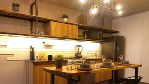 A modern kitchen with wooden cabinets, a central island with bar stools, and a dining area. - Missum Versatile Living (San Andrés Cholula)