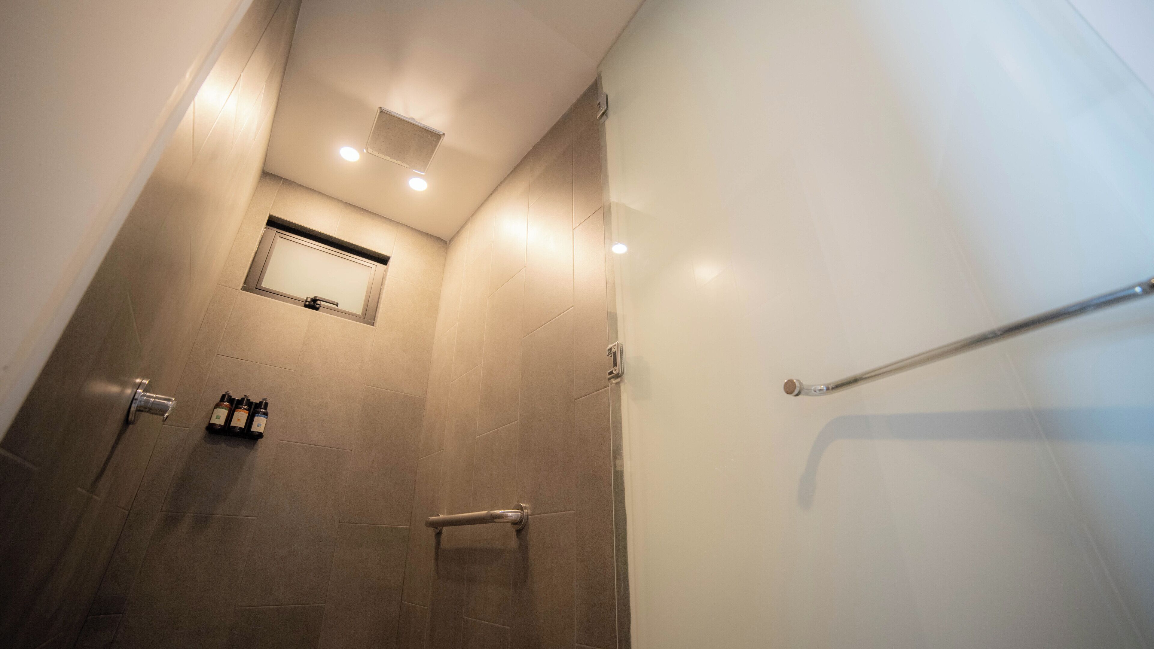 Een moderne badkamer met een douche, een handdoekhouder en een klein spiegel.