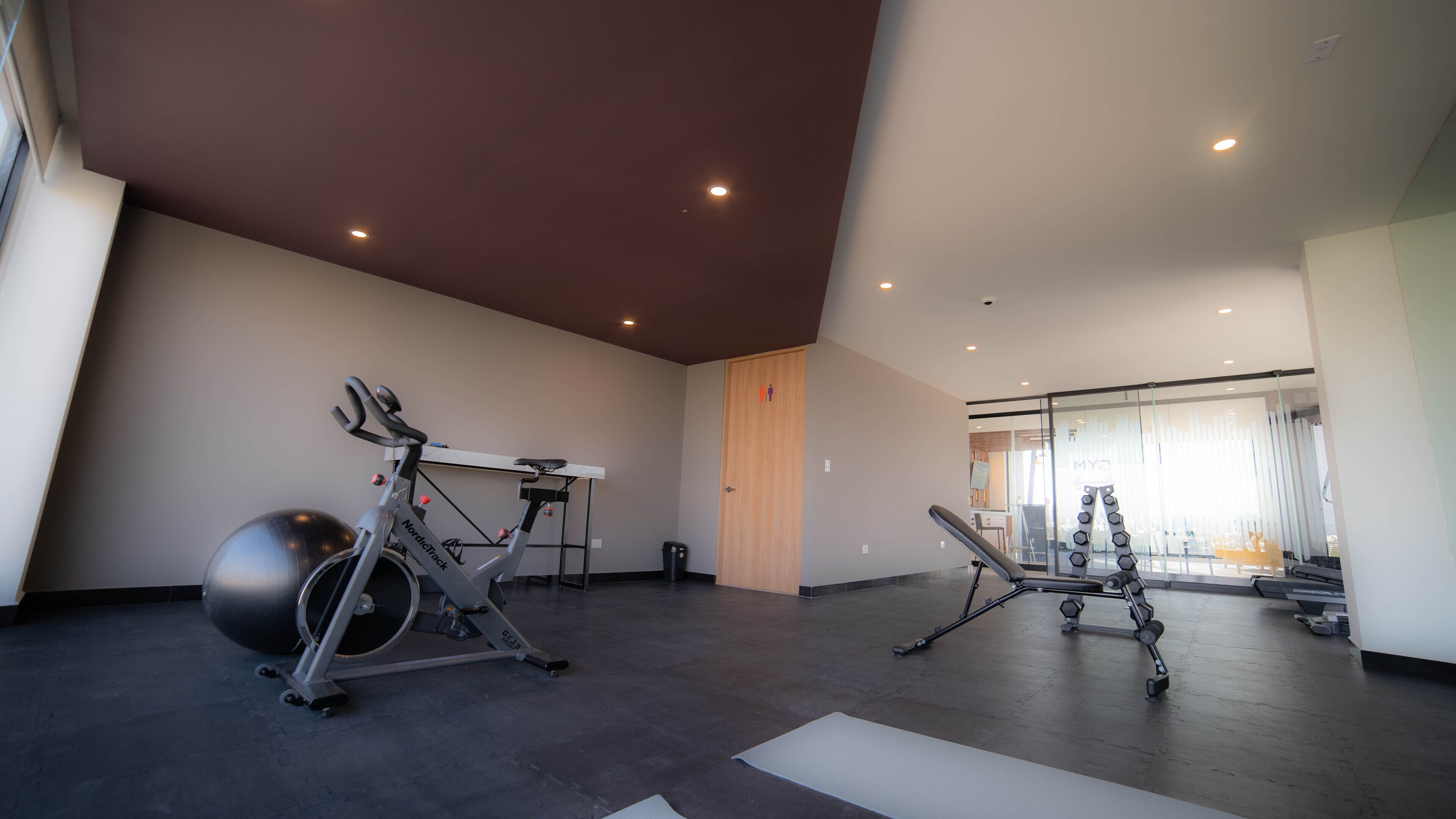 A spacious gym with cardio equipment, weight machines, and a large exercise ball.