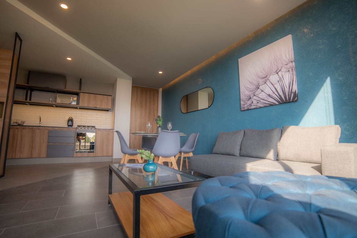 Una sala de estar moderna con un sofá, una mesa de centro y un comedor con sillas y una mesa.