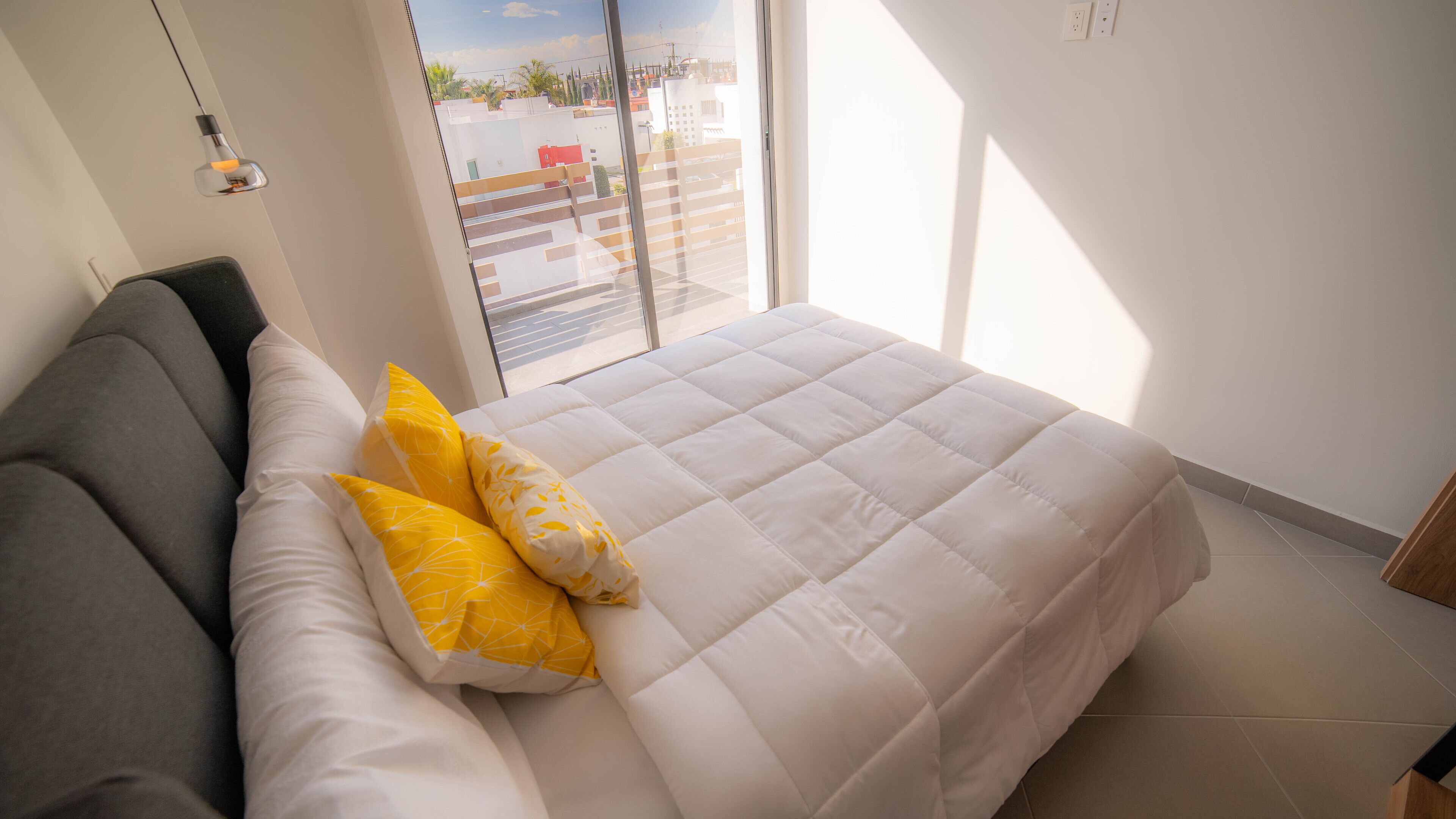 A bedroom with a bed, a sofa, and a view of the outside.
