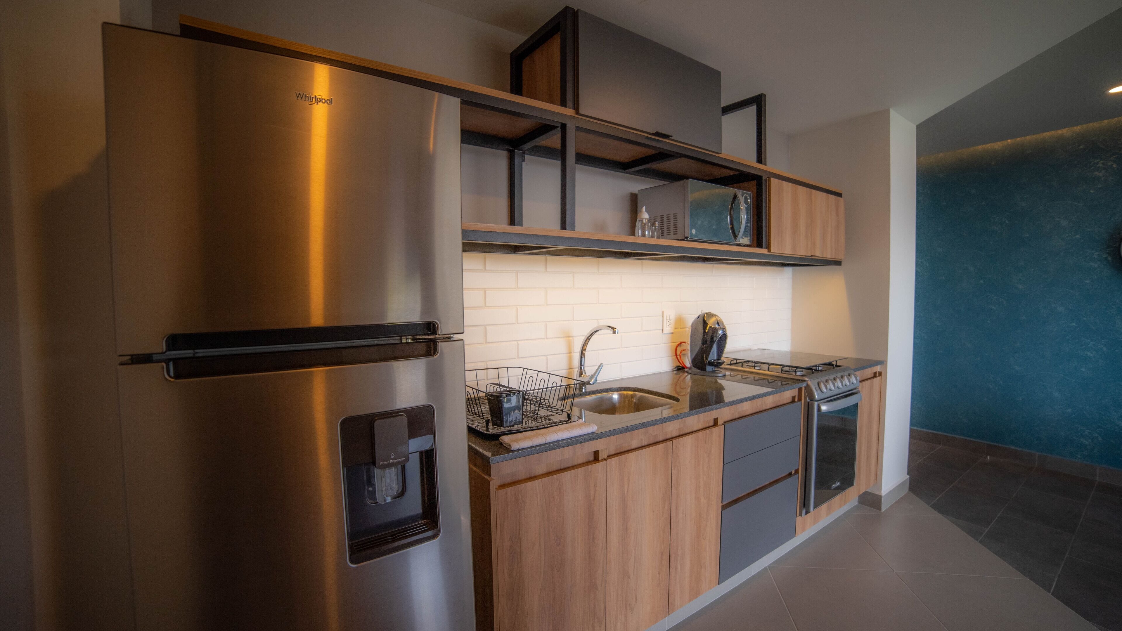A modern kitchen with a stainless steel refrigerator, a built-in dishwasher, a microwave, a gas stove, and wooden cabinetry.
