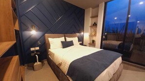 A modern bedroom with a large bed, a nightstand, a bedside table, and a window with a view. - Missum Versatile Living (San Andrés Cholula)