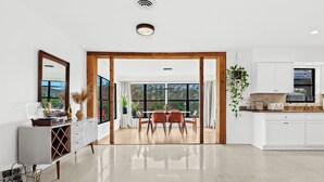 Eine moderne Küche mit weißen Schränken, einem Essbereich aus Holz und einem großen Fenster.