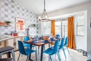 A dining area with a checkered wall, a hanging light fixture, and a table set with blue chairs and orange curtains. - Summer Promotion- XBOX room- Pets welcomed! Sleeps 18- Hottub- Hammocks (Heber City)