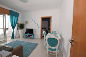 A compact living space with a dining area, a television, and a door leading to another room.