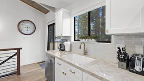 A modern kitchen with white cabinets, a large window, and a clock on the wall. - Newly Rennovated and Air Conditioned Townhouse -1 mile from Skiing (Incline Village)