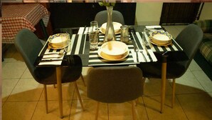 Une table à manger dressée avec des assiettes, des couverts et un vase.