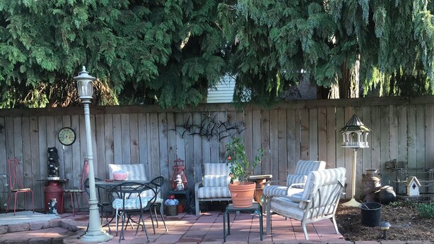 A patio with outdoor furniture, a clock, and a wooden fence. - Bungalow Guest House (Vancouver)
