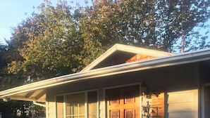 A single-story house with a porch, a bench, a small table, and a decorative door. - Bungalow Guest House (Vancouver)