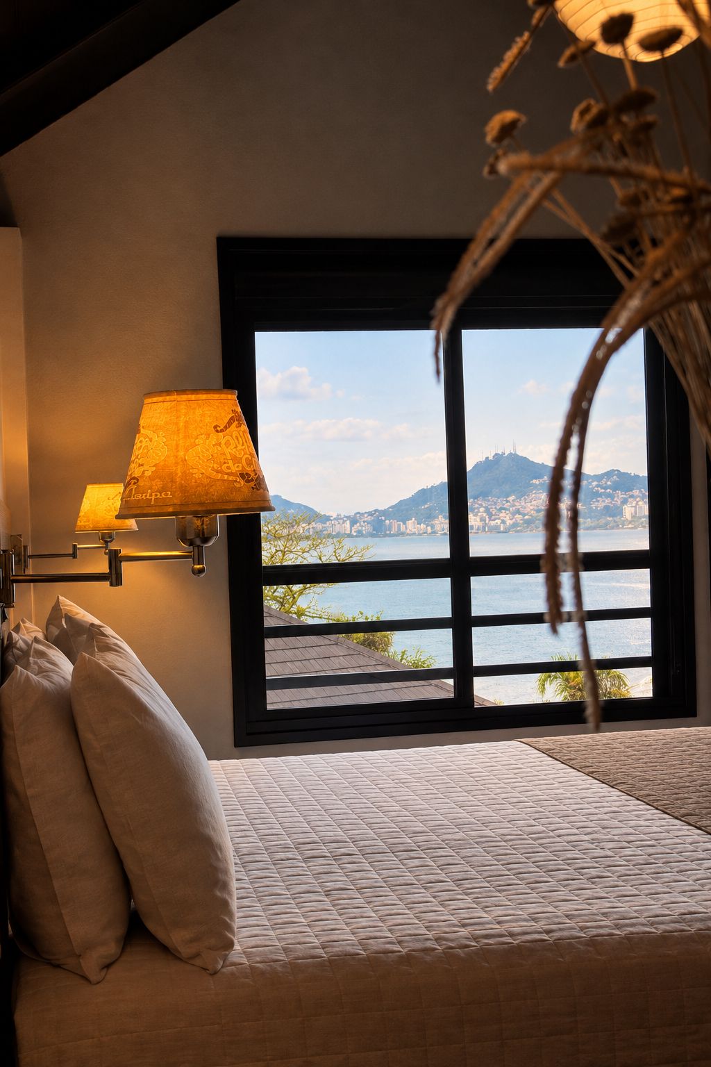 A bed with a view of a cityscape through a large window.