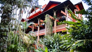 A multi-story building with a red and brown facade, surrounded by lush tropical vegetation. - Refúgio do Cacupé (Florianópolis)