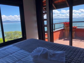 Una habitación con cama, vista al mar y balcón con plantas en macetas.