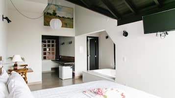 A modern bedroom with a large bed, a small kitchenette, and a bathroom with a bathtub.