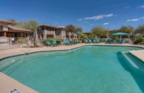 A swimming pool with lounge chairs and a fence.