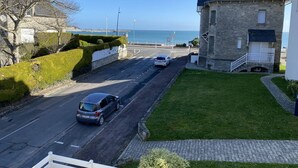 Una carretera costera con un edificio de piedra y una zona ajardinada.