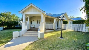 A two-story house with a covered porch, a front yard, and a white picket fence.