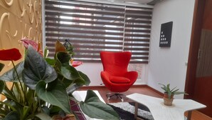 A modern living room with a red chair, a small white table, and a potted plant.