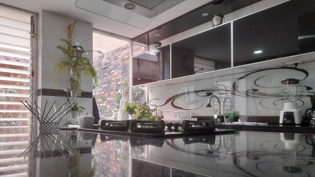 A modern kitchen with a reflective countertop, built-in appliances, and a decorative backsplash.