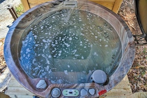 Una vasca idromassaggio con pannello di controllo, circondata da un pontile in legno.