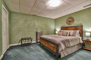 Un dormitorio con cama, mesitas de noche, un espejo y una lámpara fijada en la pared.