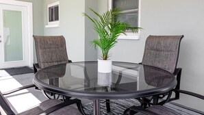 Una mesa redonda de vidrio con cuatro sillas, una planta en maceta y un ventanal pequeño.