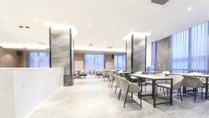 A modern hotel lobby with marble flooring, a reception desk, and a row of tables and chairs. - Busan station city hotel (Busan)