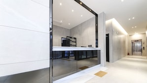 A modern hotel lobby with a reception desk, glass walls, and a visible elevator. - Busan station city hotel (Busan)
