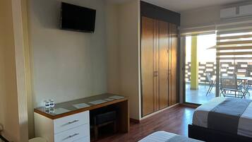 A bedroom with a bed, a desk, a wardrobe, and a TV.